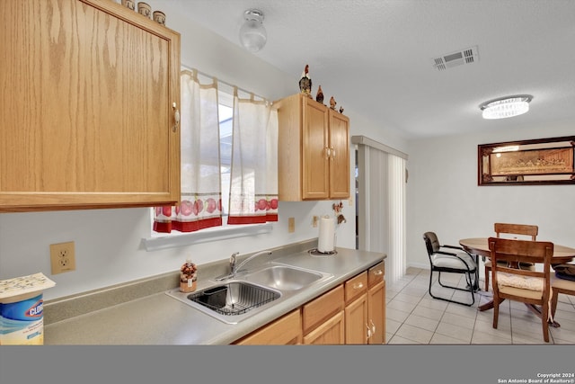 kitchen with light brown cabinetry, light tile patterned floors, a textured ceiling, and sink