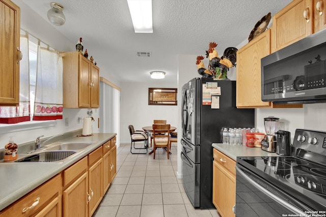 kitchen featuring sink, light tile patterned floors, black appliances, and a textured ceiling