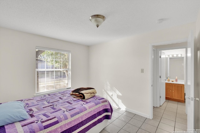 bedroom with light tile patterned floors, a textured ceiling, and ensuite bathroom