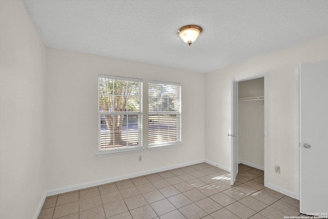 unfurnished bedroom with light tile patterned floors, a textured ceiling, and a closet