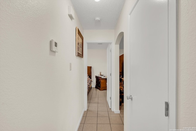 hallway with light tile patterned floors and a textured ceiling