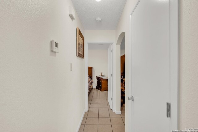 hallway with light tile patterned floors and a textured ceiling