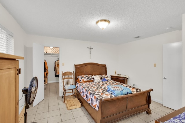 bedroom featuring light tile patterned floors, a textured ceiling, and a closet