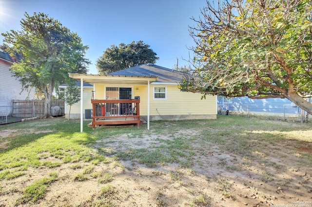 rear view of property with a yard, a wooden deck, and central AC