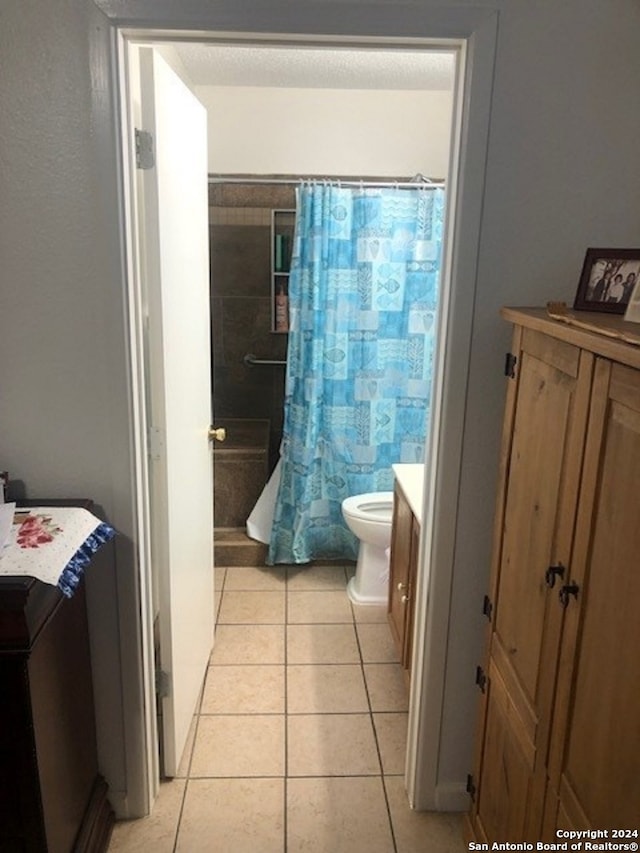 bathroom with tile patterned flooring, vanity, toilet, and curtained shower