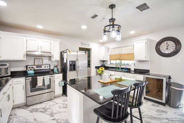 kitchen featuring appliances with stainless steel finishes, hanging light fixtures, decorative backsplash, white cabinets, and sink