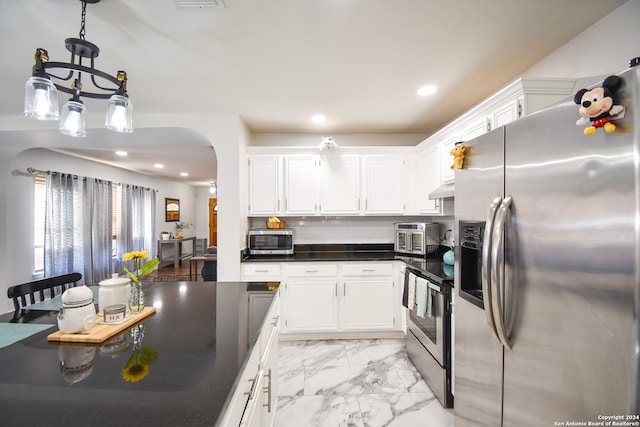 kitchen with an inviting chandelier, stainless steel appliances, white cabinetry, and decorative light fixtures