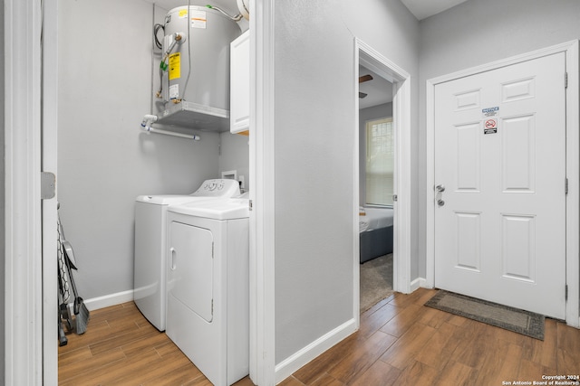 laundry area with cabinets, dark hardwood / wood-style floors, water heater, and washing machine and clothes dryer