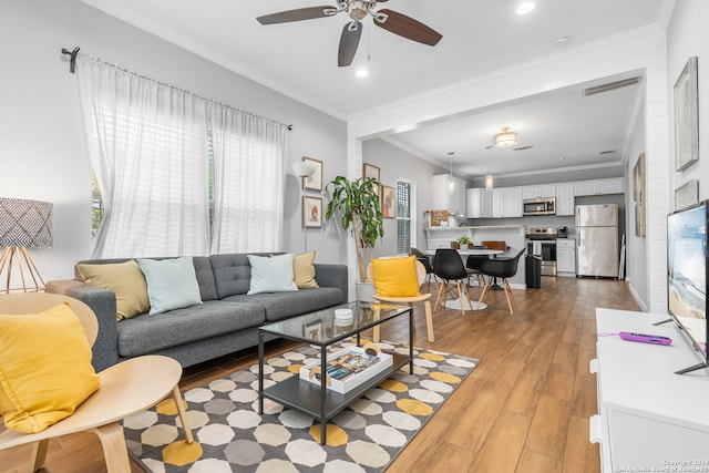 living room with ceiling fan, light hardwood / wood-style flooring, and crown molding