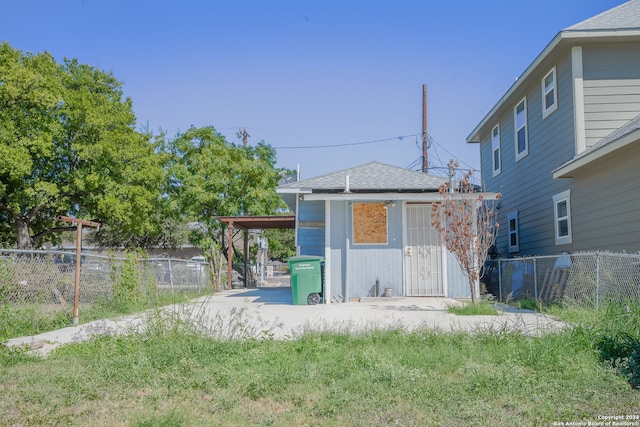 rear view of house featuring a carport and a yard