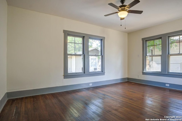 spare room with a healthy amount of sunlight, ceiling fan, and dark wood-type flooring