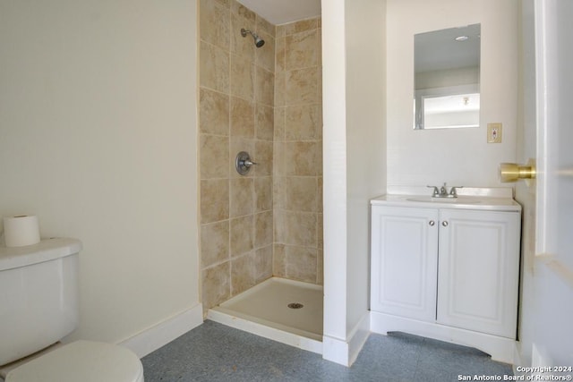 bathroom with tiled shower, vanity, and toilet