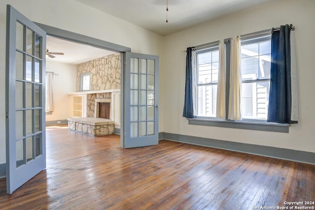 unfurnished living room with french doors, ceiling fan, hardwood / wood-style flooring, and a fireplace