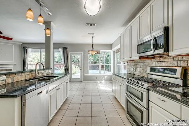 kitchen featuring pendant lighting, sink, white cabinets, backsplash, and appliances with stainless steel finishes