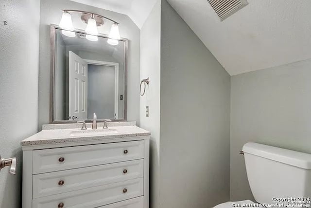 bathroom with lofted ceiling, vanity, and toilet