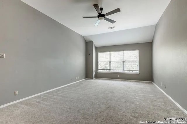 carpeted spare room featuring vaulted ceiling and ceiling fan