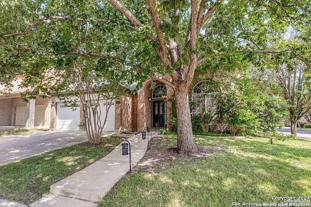 view of property hidden behind natural elements with a garage and a front lawn