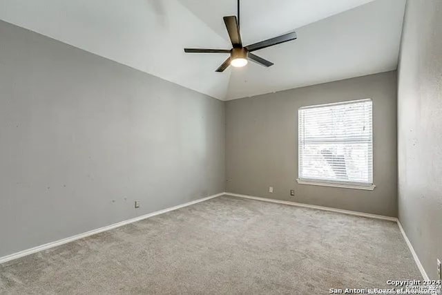 empty room featuring lofted ceiling, ceiling fan, and light colored carpet