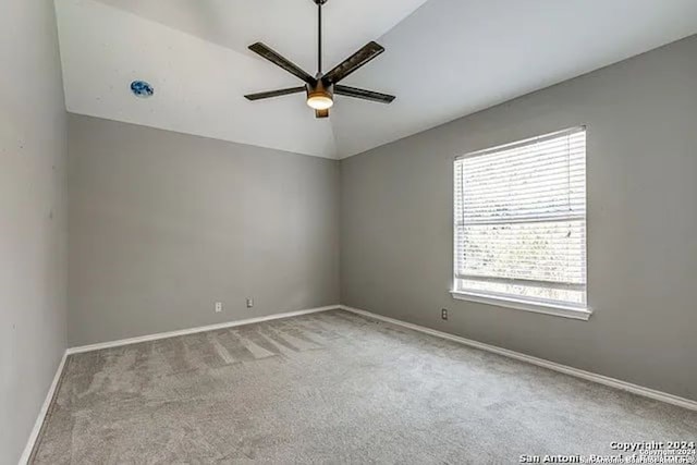 carpeted spare room featuring vaulted ceiling and ceiling fan