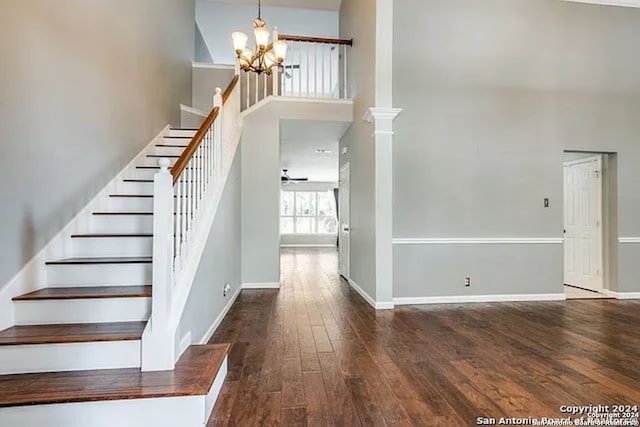 stairway with ceiling fan, decorative columns, a towering ceiling, and hardwood / wood-style floors