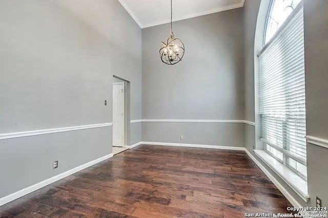 unfurnished room featuring ornamental molding, an inviting chandelier, and dark hardwood / wood-style flooring