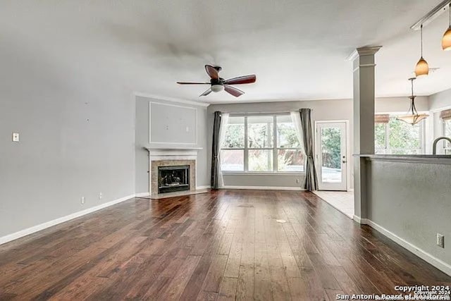 unfurnished living room with ceiling fan, ornate columns, and dark hardwood / wood-style flooring