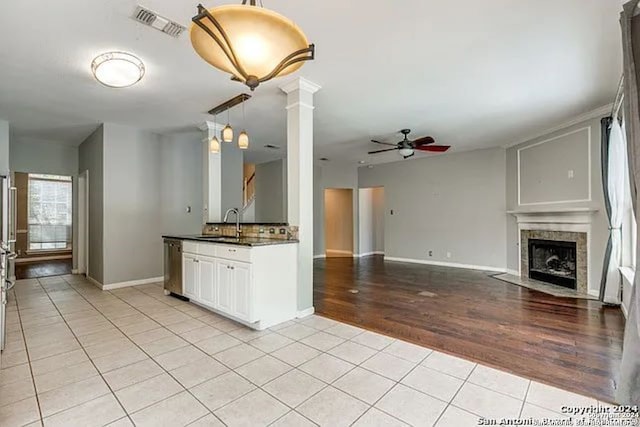 kitchen featuring light wood-type flooring, dishwasher, a tile fireplace, white cabinets, and ceiling fan