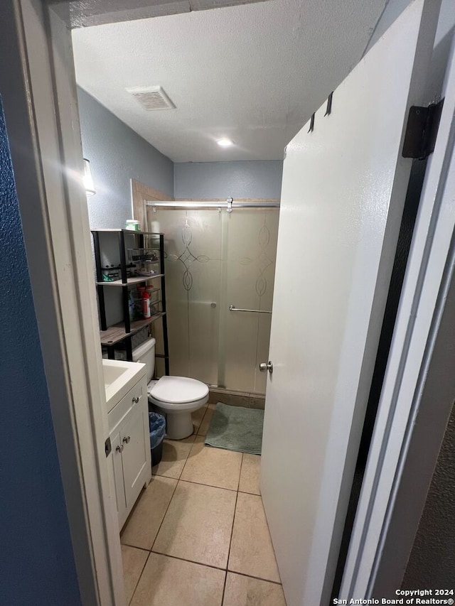 bathroom featuring walk in shower, tile patterned flooring, a textured ceiling, toilet, and vanity