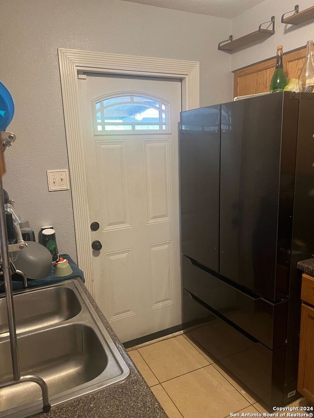 kitchen with black fridge, light tile patterned floors, and sink