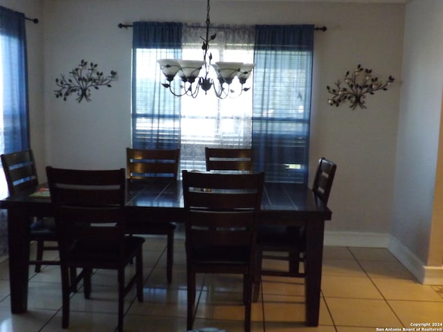 tiled dining room featuring an inviting chandelier and plenty of natural light