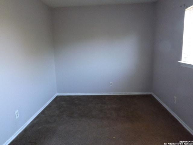 unfurnished room with dark colored carpet