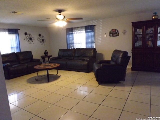 living room featuring a textured ceiling, light tile patterned floors, and ceiling fan