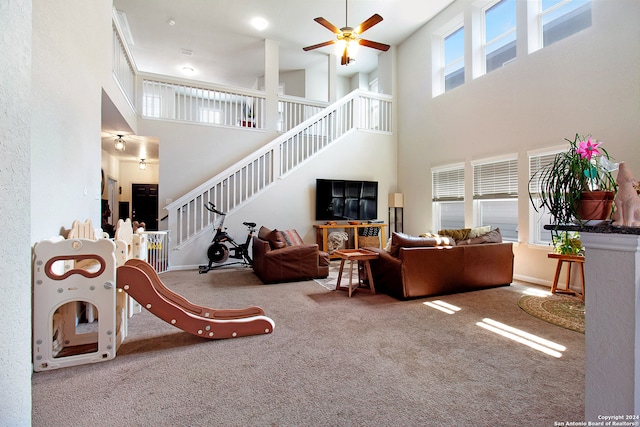 living room with carpet, a towering ceiling, and ceiling fan