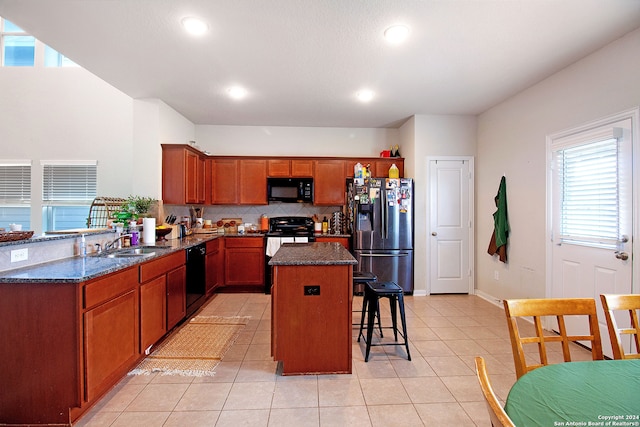 kitchen featuring kitchen peninsula, dark stone counters, sink, black appliances, and a kitchen island