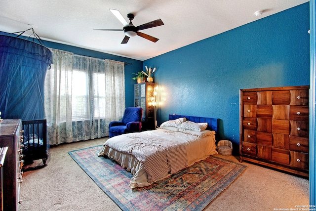 carpeted bedroom featuring ceiling fan and a textured ceiling