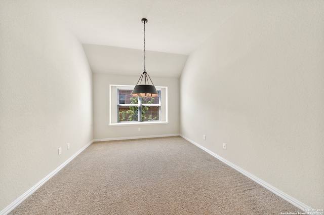 carpeted spare room with vaulted ceiling