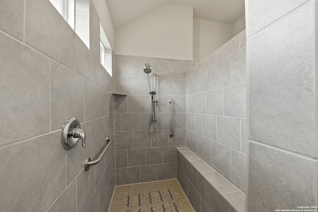 bathroom featuring lofted ceiling and a tile shower