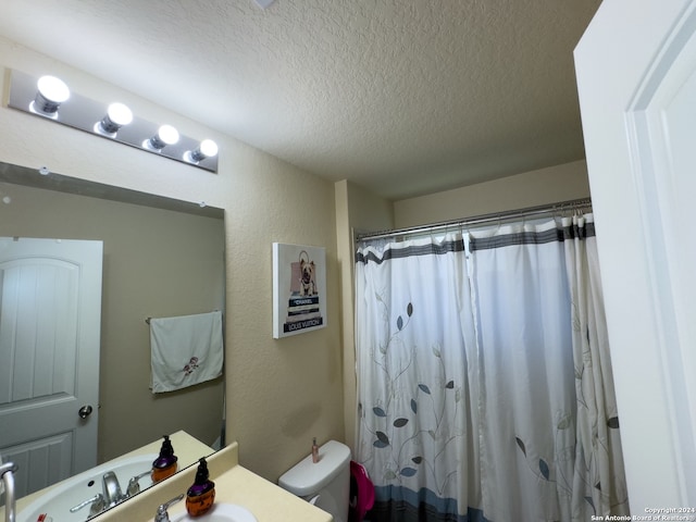 bathroom with a textured ceiling, toilet, a shower with shower curtain, and sink