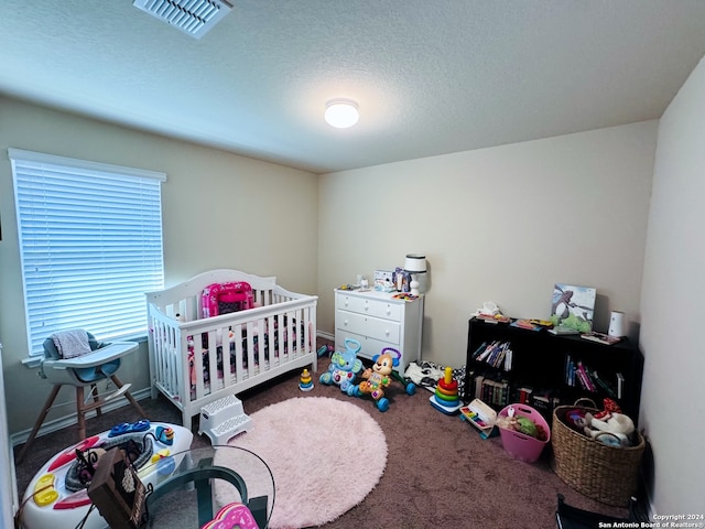 bedroom with carpet floors, a textured ceiling, and a crib