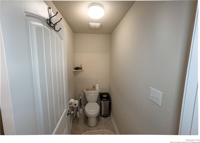 bathroom with a textured ceiling, tile patterned floors, and toilet