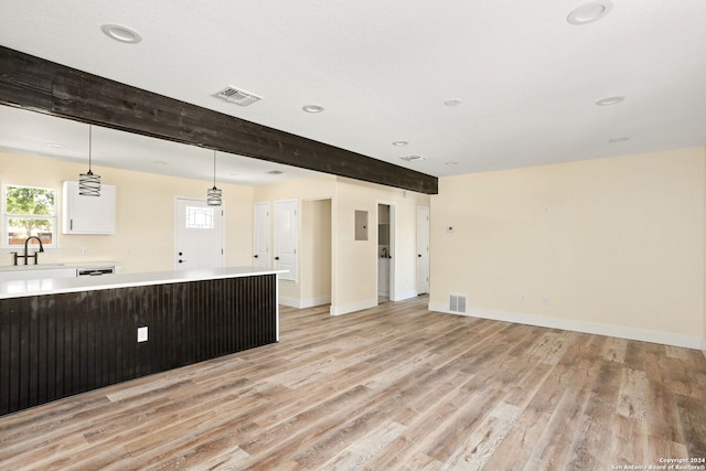 unfurnished living room with light hardwood / wood-style floors, sink, and beamed ceiling