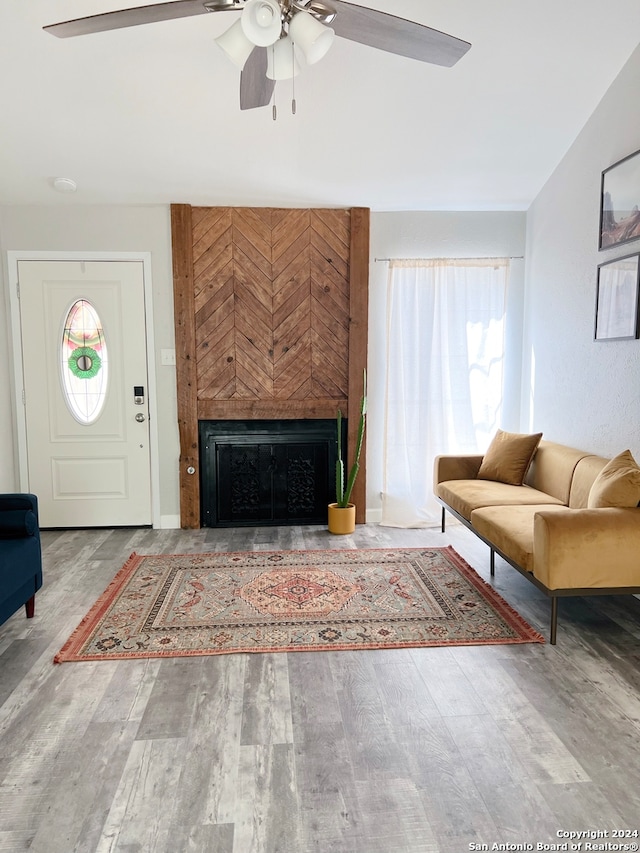 living room featuring hardwood / wood-style floors, ceiling fan, and a large fireplace