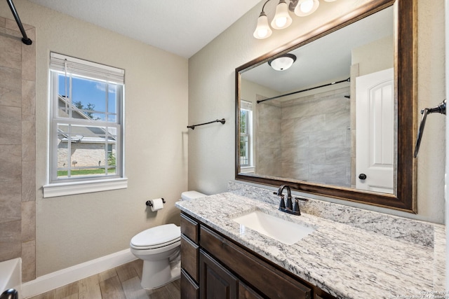 bathroom with a healthy amount of sunlight, wood-type flooring, vanity, and toilet