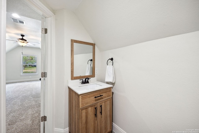 bathroom with ceiling fan, vaulted ceiling, a textured ceiling, and vanity