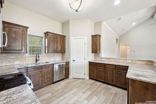 kitchen with vaulted ceiling, light stone counters, light wood-type flooring, stainless steel dishwasher, and sink