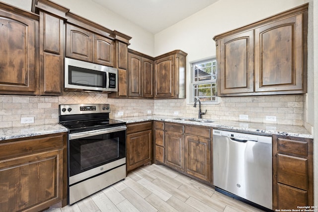 kitchen featuring light stone counters, appliances with stainless steel finishes, sink, and tasteful backsplash