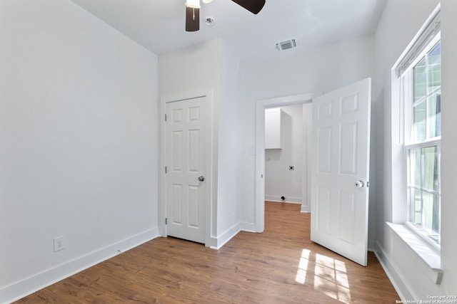 unfurnished bedroom with ceiling fan, baseboards, wood finished floors, and visible vents