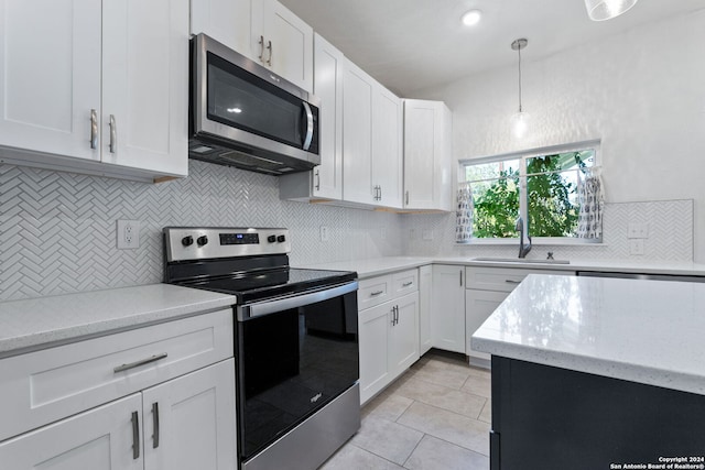 kitchen with decorative light fixtures, stainless steel appliances, decorative backsplash, and white cabinetry