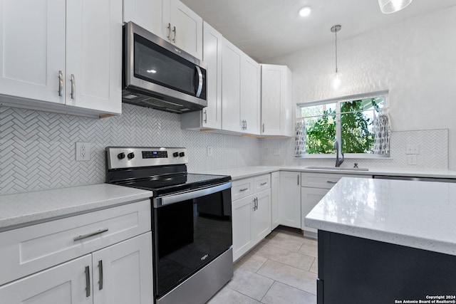 kitchen featuring white cabinets, light tile patterned floors, a sink, tasteful backsplash, and appliances with stainless steel finishes