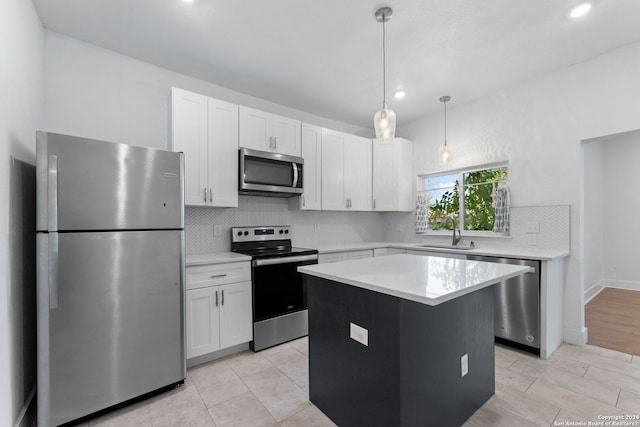 kitchen with a center island, sink, white cabinetry, appliances with stainless steel finishes, and decorative light fixtures